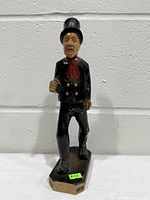 Front view of carved wooden chimney sweep figurine showing top hat, clothing, and base inscription.