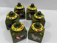 Six green square ceramic canisters with rooster decoration, lids on