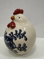 Front three-quarter view of cream ceramic rooster with blue floral design