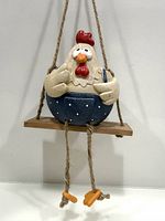Front view of ceramic chicken planter on wooden swing showing full form and colors