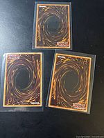 Card backs showing swirl design of three Yu-Gi-Oh! cards in sleeves