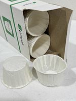 Open box showing stacked white paper cups and two cups displayed outside
