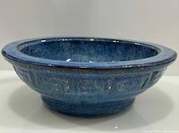 Side profile of deep-blue glazed ceramic bowl showing relief pattern and rim