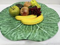 front view of large green leaf-shaped platter with fruit props