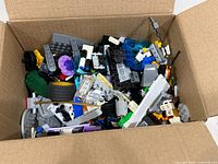 Open cardboard box filled with assorted LEGO parts