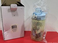 Bottle in plastic wrap beside original white box