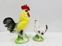 Front view of rooster and hen figurines showing colours and stance