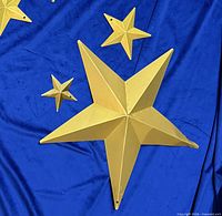 Three gold metal stars displayed on blue cloth