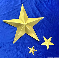 Three gold metal stars laid flat showing size differences