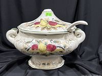 Full view of soup tureen with lid and ladle showing fruit motif and handles