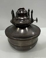 front view of metal oil lamp base showing burner, gallery arms, reservoir
