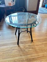 Single round glass accent table with glass top and metal scroll base