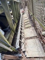 Full view of aluminum extension ladder lying collapsed along fence