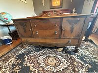 Front view showing cabinet doors, drawers, carved details, bun feet