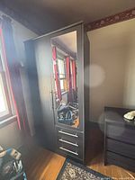 Front view of black wardrobe showing mirrored door and drawers