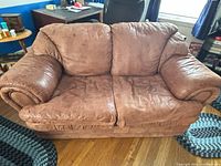 Front view of brown microfiber loveseat showing rolled arms and nailhead trim