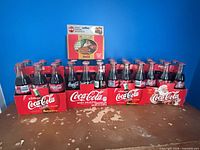 All three 6-packs of Coca-Cola bottles and the playing card tin