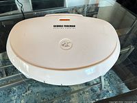 Closed George Foreman GR1212CAN grill on glass table