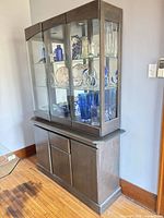 Full front view of gray wood and glass china cabinet showing three glass doors and lower storage