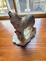 Front view of wolf and pup resin figurine on wooden surface