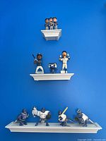 Overview of three white shelves on blue wall holding entire bobblehead collection