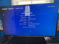 TV powered on showing Roku system info screen with model and software details