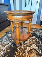 Three-quarter view of oval two-tier side table showing top, legs, shelf