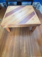 Top view of square solid wood coffee table showing two-tone diagonal plank surface
