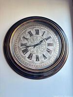 Front view of round ornate wall clock showing full frame and dial