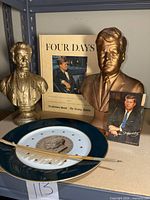 Group shot of both busts, plate, pen, postcard, book