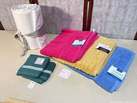 Rolled bedding, four bath towels in assorted colors, folded washcloths, visible brand tags
