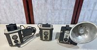 Front view of all three Kodak Brownie cameras showing overall condition and attached flash units