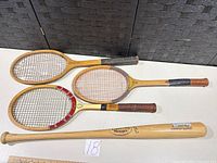 Overview of three Bancroft rackets and one Louisville Slugger bat