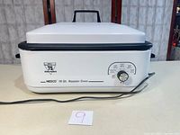 Front view of Nesco 18-quart roaster oven showing exterior, lid, knob, logo and power cord