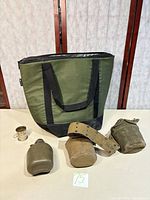 Group shot of cooler tote, canteens, pouches, belt and cup