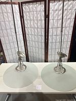 Both pendant lights showing full length rods, brushed nickel hardware and frosted glass disc shades