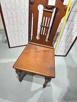 Front view of solid wood Victorian revival dining chair showing carved backrest and missing seat