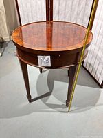 Full view of round mahogany side table with measuring tape for scale