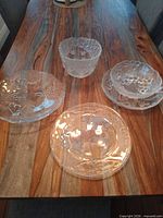 Overview of four pressed glass pieces on table showing motifs and sizes