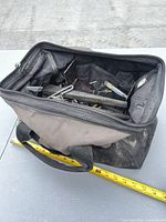 Soft tool bag open with contents visible, tape measure for scale