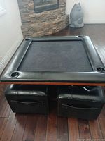 Game table with ottomans tucked underneath, showing faux leather rail and cup holders