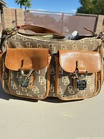 Front view showing monogram canvas, leather trim, two flap pockets, lock hardware