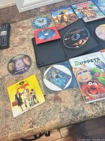 Overview showing Muppets case, Kung Fu Panda 2 disc, Unfaithful case with disc, additional loose discs