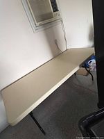 Full view of 6-ft beige folding table against wall