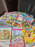 Overview of entire lot on round table showing mix of puzzles and activity pads