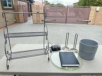 All items overview on table: metal shelf, clock, book, glass lazy susan, two paper-towel holders, two fabric boxes