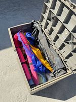 Open gray plastic storage tote showing contents of pool noodles and inflatables