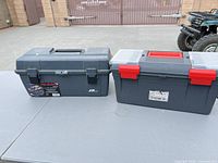 Two closed gray plastic toolboxes on table