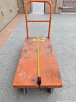 Top view of orange flatbed cart with tape measure indicating 48in length, visible casters and wear