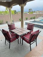 Full view of square tile-top table and four chairs with cushions and pillows